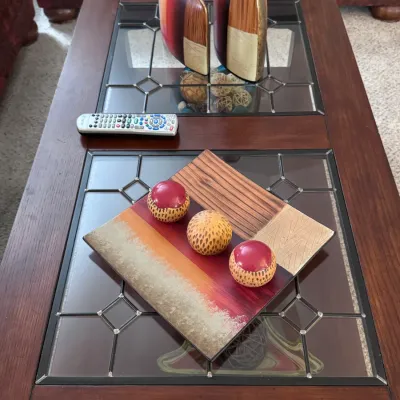 Contemporary wooden coffee table featuring a rich cherry finish, inset leaded glass panels, and a lower display shelf, styled with modern...