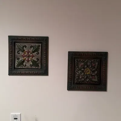 Pair of square, Tuscan-style molded wall plaques featuring ornate relief medallions with acanthus leaf and floral motifs in muted green,...