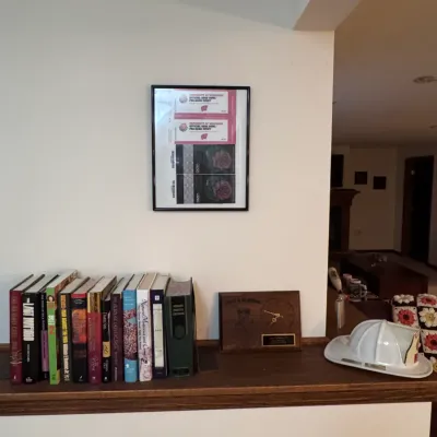 Framed Rose Bowl memorabilia, including University of Wisconsin pre-game event tickets, displayed above a wooden shelf holding a row of...