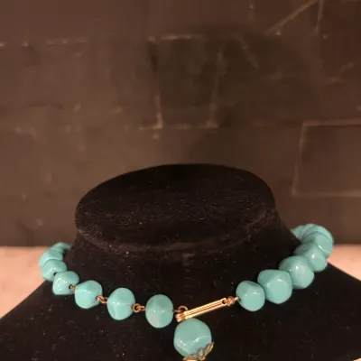 Vintage turquoise-colored molded plastic bead choker necklace with a gold-tone metal clasp and a single hanging bead charm.