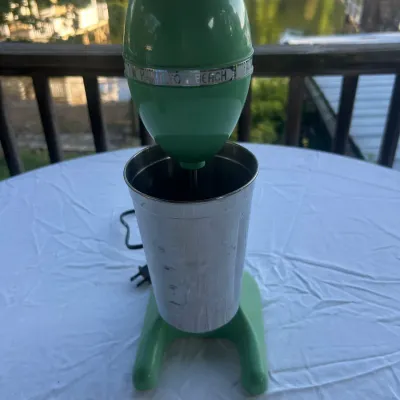 Vintage Hamilton Beach milkshake mixer in jadeite green, complete with a stainless steel mixing cup.