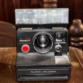 Vintage Polaroid Pronto! RF Land Camera with attached flash bar, showing some dust and wear from age.