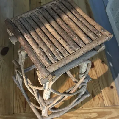 Rustic Adirondack-style twig plant stand or small side table, featuring a square slatted top and curved branch supports.
