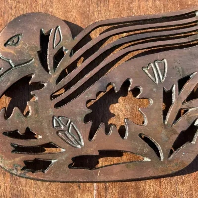 Vintage cast brass or bronze duck-shaped trivet featuring decorative cutouts of flowers and foliage.