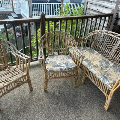 Vintage wicker patio set including a loveseat and two armchairs, featuring patterned fabric cushions on two of the pieces.