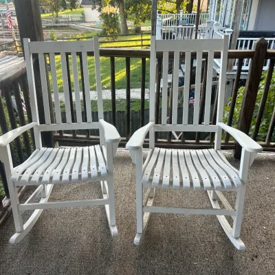 Pair of white-painted wooden rocking chairs with slatted seats and backs, showing some light outdoor wear.