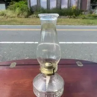 Vintage clear glass oil lamp with a textured base, brass-tone burner assembly, and a classic glass chimney.