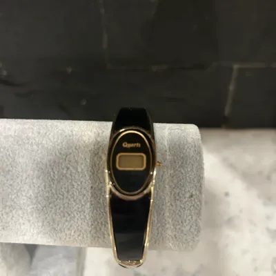 Vintage Quartz digital bangle watch featuring a black and gold-tone oval face and matching band.