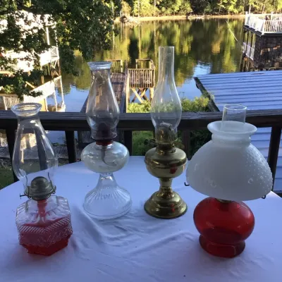 Collection of four vintage oil lamps, including a red pressed glass base, a clear ribbed glass pedestal lamp, a brass-finished lamp, and...