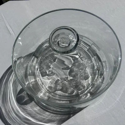Vintage clear glass cake dome or covered dish featuring an embossed floral rose pattern on the top surface and a ribbed border.