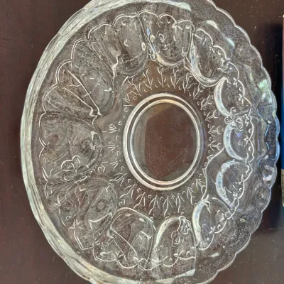 Vintage clear pressed glass deviled egg platter with a scalloped rim and textured floral details.