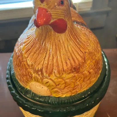 Vintage ceramic hen on nest cookie jar, featuring a detailed brown and yellow speckled hen sitting on a woven basket base with green trim.