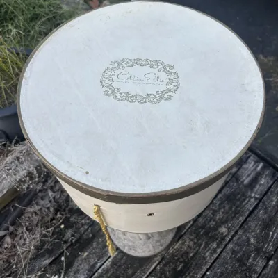 Vintage round cardboard hat box from Collier Ellis and Company, featuring a cream-colored lid with an ornate logo and a yellow cord handle.
