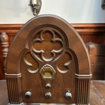 Philco cathedral-style replica radio in a wooden cabinet, featuring AM/FM bands and a decorative gothic arch grille.