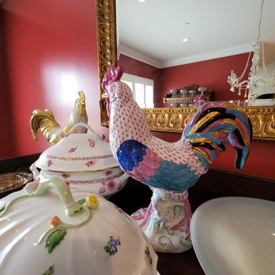 Herend porcelain rooster figurine featuring a pink fishnet pattern with vibrant blue, pink, and gold tail feathers, displayed alongside...
