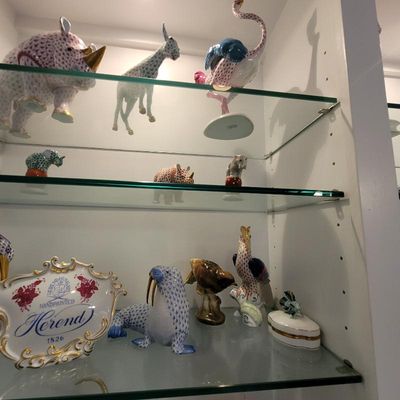 Collection of Herend Hungary hand-painted porcelain animal figurines, including a rhinoceros, giraffe, ostrich, and walrus, displayed on...