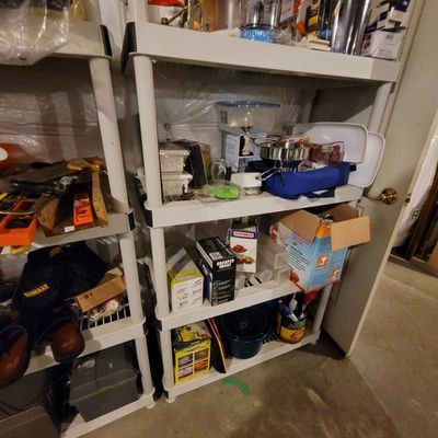 White plastic shelving units holding various household items, kitchen gadgets, and tools.