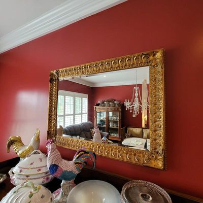 Large rectangular wall mirror featuring an ornate, gilded frame with intricate scrollwork and egg-and-dart detailing.