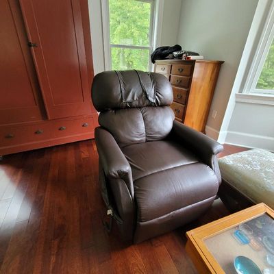 Plush brown faux-leather power lift recliner chair, showing minor wear on the headrest.