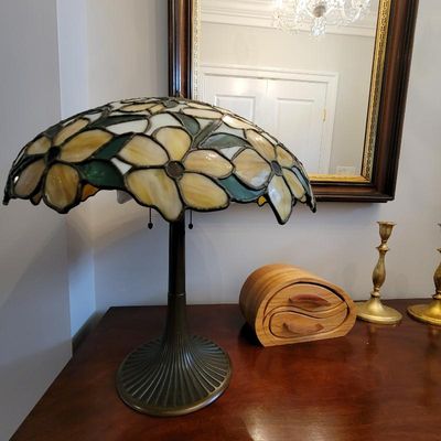 Tiffany-style table lamp featuring a leaded stained glass shade with a yellow and green floral motif, set on a fluted bronze-finished base.