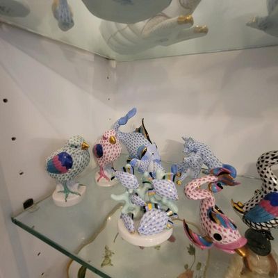 Collection of Herend porcelain animal figurines featuring their signature fishnet pattern, displayed on a glass shelf.