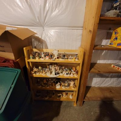 A collection of small porcelain and ceramic figurines, including various characters and village scenes, displayed on a four-tier light...