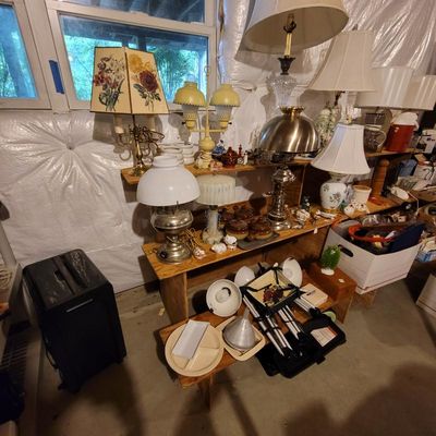 Assortment of vintage table lamps, including hurricane-style lamps, floral-patterned shades, and brass bases, displayed on wooden...