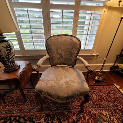 Louis XV style armchair featuring light blue and gold floral damask upholstery, carved wood frame, and cabriole legs.