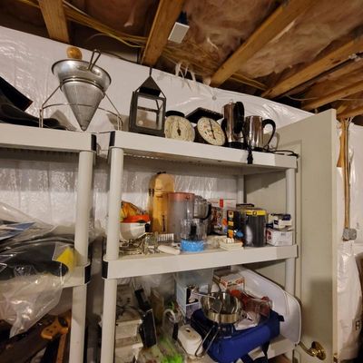 Assorted kitchenware and household items on plastic shelving, including a vintage metal chinois strainer, kitchen scales, and small...
