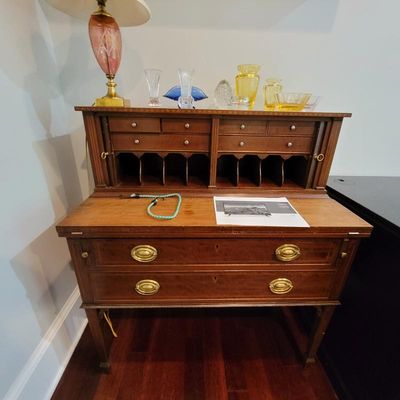 Federal-style mahogany secretary desk featuring a fold-out writing surface, multiple small drawers, mail slots, and two large lower...
