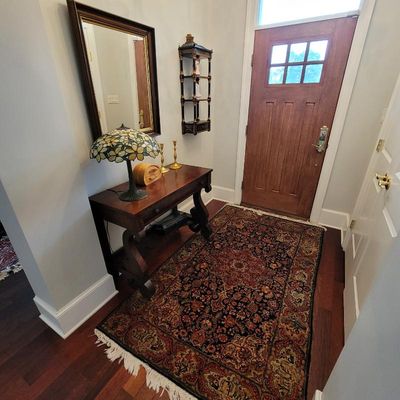 Traditional entryway featuring a dark wood console table, a Tiffany-style stained glass table lamp, a gold-framed wall mirror, and a...