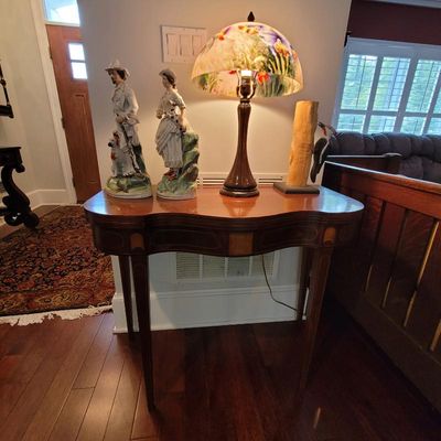 Federal-style mahogany card table with string inlay, displaying a pair of porcelain figurines, a reverse-painted glass table lamp, and a...
