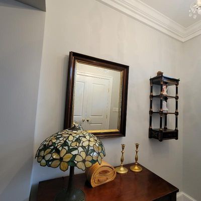 Tiffany-style stained glass table lamp with a floral motif, displayed alongside a wooden jewelry box, brass candlesticks, a dark wood...