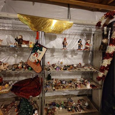 Assorted Christmas decorations, including nutcrackers, ornaments, and a needlepoint stocking, displayed on wire shelving.