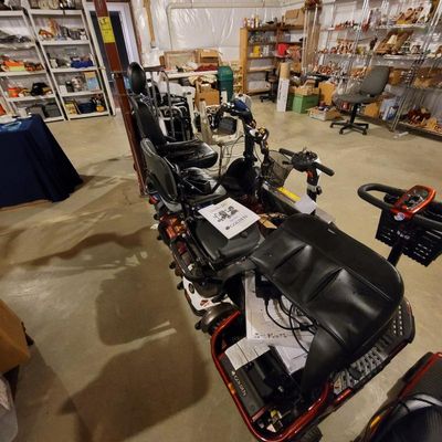 Golden Technologies LiteRider mobility scooter in red, shown with its manual and accessories in a basement setting.