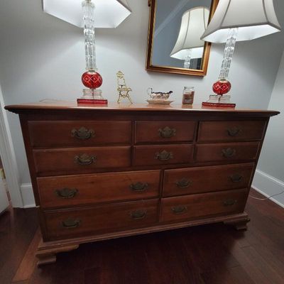 Traditional cherry wood dresser featuring nine drawers with brass batwing pulls, styled with a pair of vintage crystal and red glass...