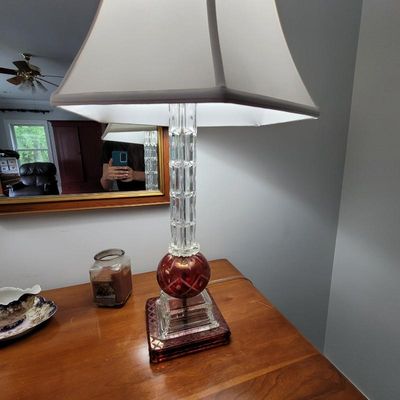 Vintage table lamp featuring a clear cut-glass column, a ruby red cut-to-clear glass sphere detail, and a matching red glass base, topped...