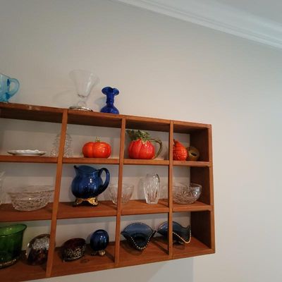 A collection of vintage glassware and ceramics, including cut crystal bowls, cobalt blue pitchers, and pumpkin-shaped dishes, displayed...