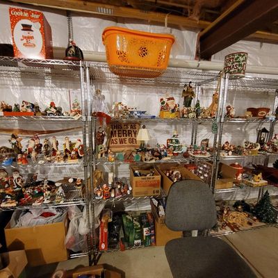 Large collection of vintage and modern Christmas decorations, figurines, and holiday decor displayed on wire shelving units.