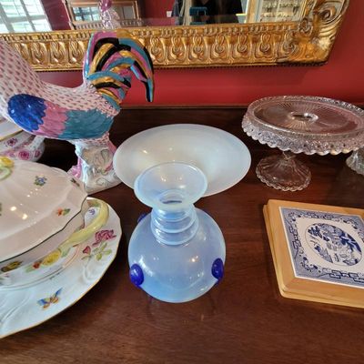 Assorted vintage tabletop decor, including a blue opalescent glass vase, a cut glass cake stand, a colorful ceramic rooster figurine, and...