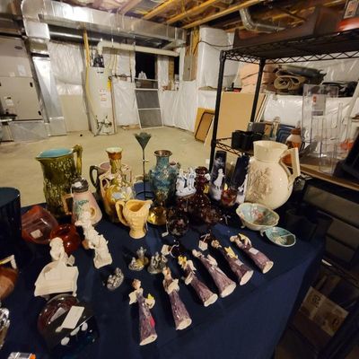 Assorted vintage glassware, ceramics, and figurines, including decorative pitchers, vases, and small angel statues, displayed on a table...