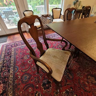 Queen Anne style wooden dining armchair with a splat back and patterned fabric seat cushion, shown alongside a matching dining table.