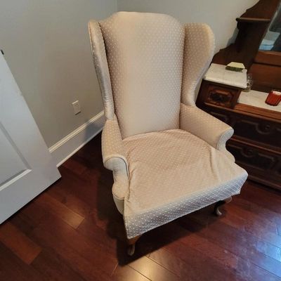 Vintage wingback armchair upholstered in a beige and white polka dot fabric, featuring cabriole legs.