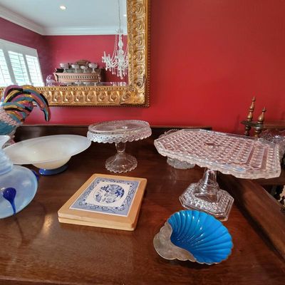 Assorted vintage glassware and decorative items, including two crystal cake stands, a blue enamel shell-shaped dish, and a blue and white...