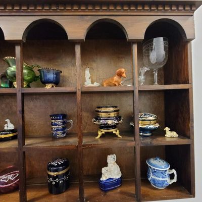 Vintage wooden shadow box shelf filled with various small collectibles, including porcelain animal figurines, cobalt blue glassware, and...