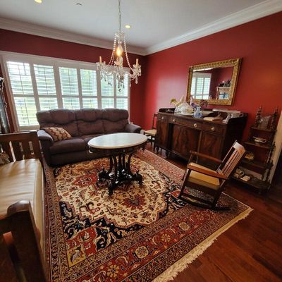 Traditional dining or sitting room featuring a large Persian-style area rug, a dark wood sideboard with a gold-framed mirror above, a...