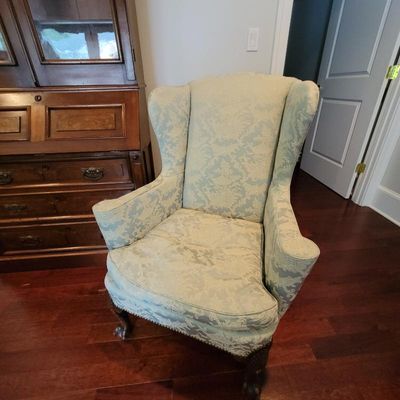 Traditional wingback armchair upholstered in a light blue and cream damask fabric, featuring carved cabriole front legs.
