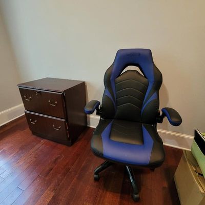 Emerge blue and black faux leather gaming chair with adjustable armrests, paired with a two-drawer dark wood filing cabinet.