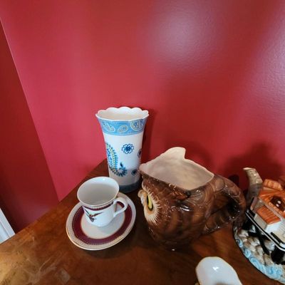 Assorted ceramic items including a blue and white paisley vase, a brown owl-shaped pitcher, and a small teacup with saucer.
