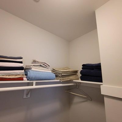 Assorted bed linens and towels, including sheets, blankets, and bath towels, neatly folded on a closet shelf.